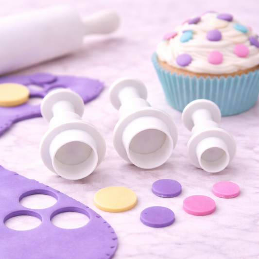 Kreisausstecher mit Auswerfer im Einsatz zur Dekoration eines Cupcakes mit bunten Fondantkreisen auf heller Arbeitsfläche