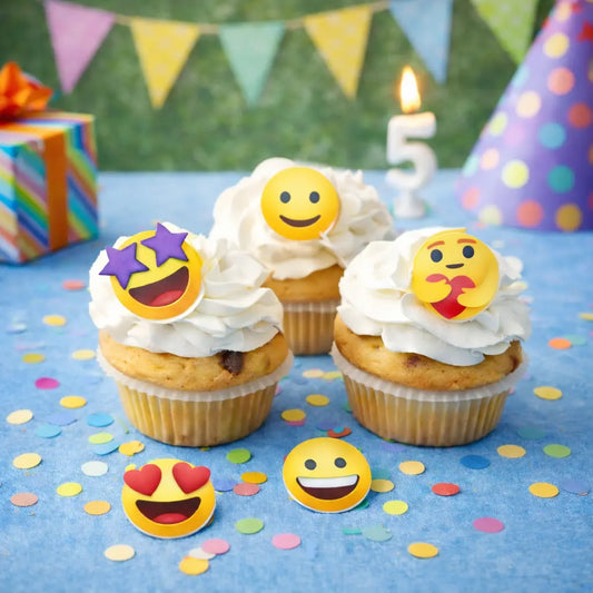 Essbare Muffinaufleger mit bunten Smiley-Motiven auf Vanillemuffins mit weißem Frosting – ideale Dekoration für Kindergeburtstage.