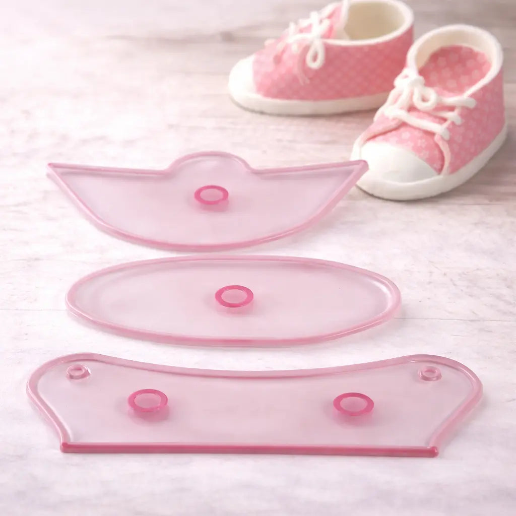 „Fondant Ausstecher Set für Babyschuhe – drei transparente Ausstecherteile mit dekorativen Babyschuhen im Hintergrund“