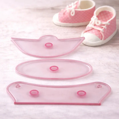 „Fondant Ausstecher Set für Babyschuhe – drei transparente Ausstecherteile mit dekorativen Babyschuhen im Hintergrund“