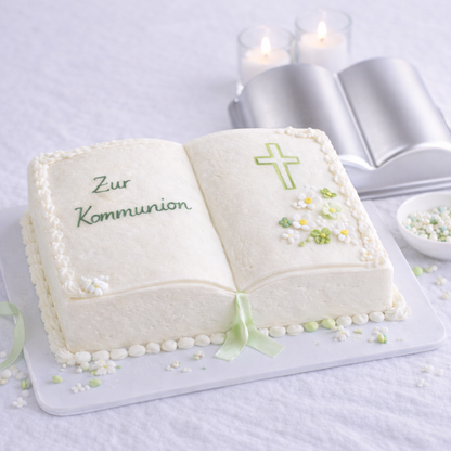 Buchförmige Kommuniontorte mit grüner Dekoration und sichtbarer Aluminium-Backform im Hintergrund