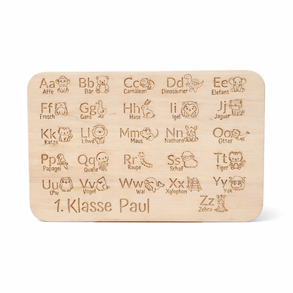 Personalisiertes Frühstücksbrettchen „Lesen lernen“ mit Alphabet-Motiv und Name „1. Klasse Paul“, freigestelltes Hauptbild mit leichtem Schatten