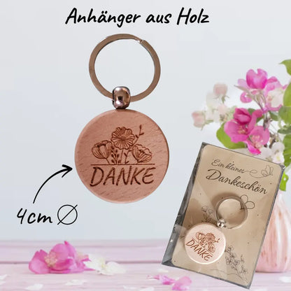 runder holz-schlüsselanhänger mit gravur danke und blumenmotiv, geliefert auf dekorativer karte ein kleines dankeschön – nachhaltiges wichtelgeschenk.