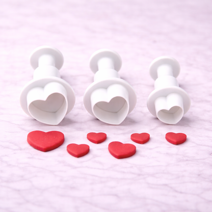 Drei Herz-Ausstecher mit Auswerfer in unterschiedlichen Größen für Fondant- und Tortendekoration auf hellem Hintergrund
