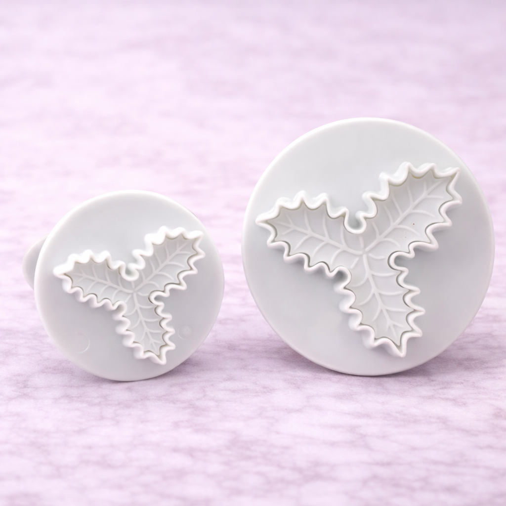 Zwei Stechpalmen-Ausstecher mit Auswerfer in unterschiedlichen Größen für Fondant- und Tortendekoration auf hellem Hintergrund