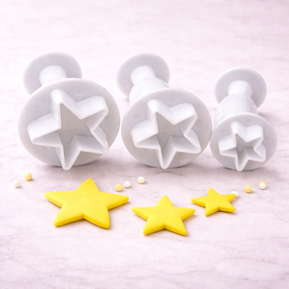 Drei weiße Stern-Ausstecher mit Plunger-Funktion in unterschiedlichen Größen für Fondant- und Tortendekoration auf hellem Hintergrund