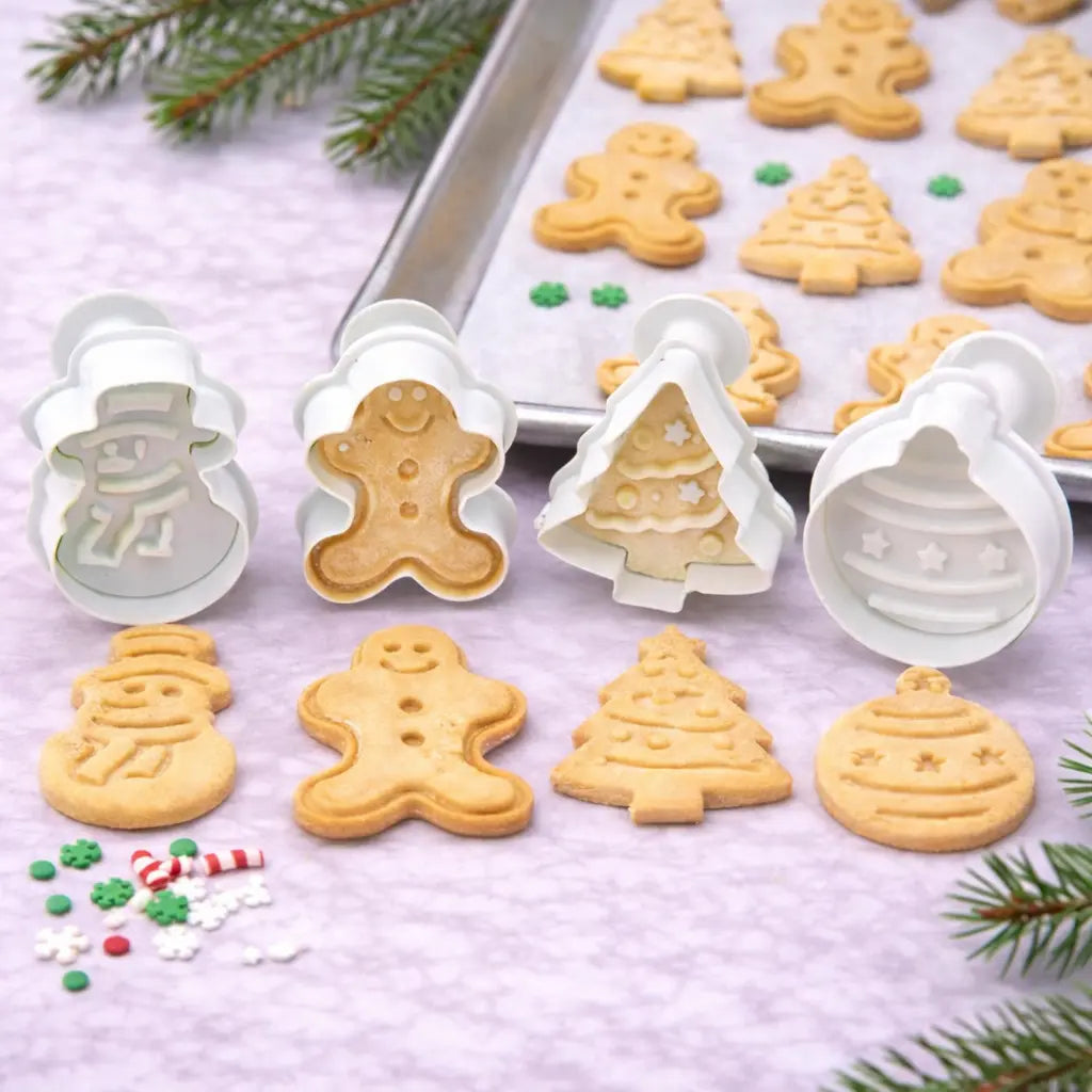 Weihnachtsbäckerei mit Keksausstechern und Stempelmotiven, frisch gebackene Weihnachtskekse auf Backblech mit weihnachtlichen Streuseln